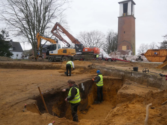Κατά τη διάρκεια των εργασιών κατεδάφισης (στο φόντο), εξετάζονται τα πρώτα στοιχεία της τομής. Στο πρώτο πλάνο, απεικονίζεται ένα σύμπλεγμα τάφρων που αποτελείται από τρεις λακκούβες και σύνθετη επανεπίχωση. Φωτογραφία: EggensteinEsca GmbH / M. Zur-Schaepers
