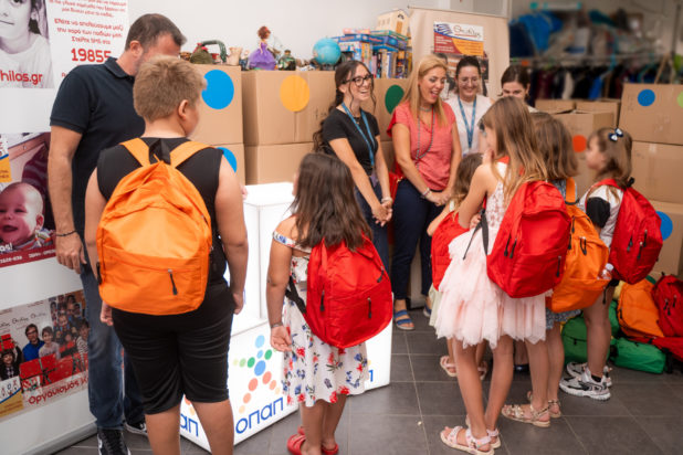 Οι εργαζόμενοι του ΟΠΑΠ μοιράζουν τις τσάντες με τα σχολικά είδη στα παιδιά του Οργανισμού