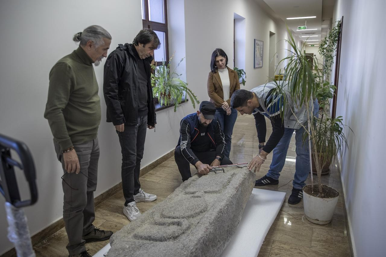 Αρχαιολόγοι εξετάζουν και μετρούν ένα θραύσμα σαρκοφάγου που ανακτήθηκε από την ακτογραμμή του φρουρίου Pertek αφού τα νερά της λίμνης του φράγματος Keban υποχώρησαν στην Tunceli της Τουρκίας, 11 Δεκεμβρίου 2025. Φωτογραφία: ΑΑ 