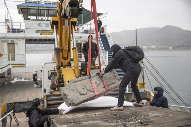 Εργάτες χρησιμοποιούν γερανό φορτωμένο σε πλοίο (φέρι μποτ) για να ανυψώσουν ένα βαρύ θραύσμα σαρκοφάγου που αναδύθηκε αφού υποχώρησαν τα νερά της λίμνης του φράγματος Keban κοντά στο φρούριο Pertek στην Tunceli της Τουρκίας, 11 Δεκεμβρίου 2025. Φωτογραφία:ΑΑ