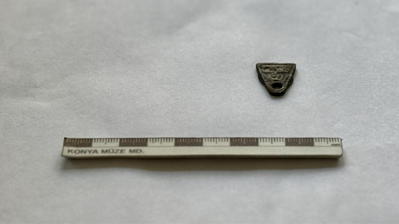 Ένα χάλκινο τριγωνικό φυλακτό, που πιστεύεται ότι χρονολογείται στη Σελτζουκική περίοδο, εμφανίζεται δίπλα σε κλίμακα μέτρησης μετά την ανακάλυψή του στη Λύστρα, στο Ικόνιο (Konya) της Τουρκίας, στις 9 Φεβρουαρίου 2026. (Φωτογραφία: AA)