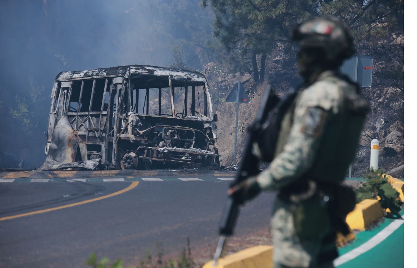 Ένας στρατιώτης στέκεται φρουρός δίπλα σε απανθρακωμένο όχημα που πυρπολήθηκε στο Κοϊντσίο, στην πολιτεία Μιτσοακάν του Μεξικού, την Κυριακή 22 Φεβρουαρίου 2026, μετά τον θάνατο του ηγέτη του καρτέλ Jalisco New Generation, Νεμέσιο Ρουμπέν Οσεγκέρα Σερβάντες, γνωστού ως «El Mencho». (Φωτογραφία: AP / Armando Solis)