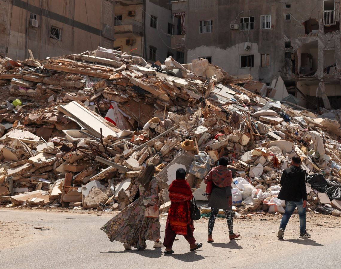 Άνθρωποι περπατούν δίπλα στα ερείπια ενός κτιρίου που καταστράφηκε από ισραηλινή επιδρομή στην Τύρο του Λιβάνου, εν μέσω κλιμάκωσης των εχθροπραξιών μεταξύ Ισραήλ και Χεζμπολάχ, καθώς συνεχίζεται η σύγκρουση ΗΠΑ-Ισραήλ με το Ιράν. Φωτογραφία: Yara Nardi/Reuters