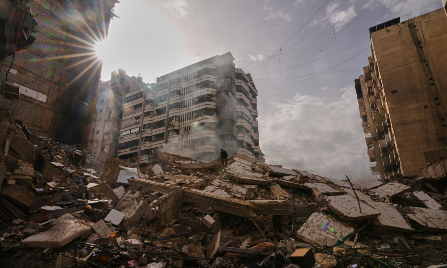 Ένας άνδρας στέκεται πάνω στα ερείπια καθώς καπνός ανεβαίνει από ένα κτίριο που καταστράφηκε σε ισραηλινή αεροπορική επιδρομή στην Νταχίγιε, στα νότια προάστια της Βηρυτού, στον Λίβανο. Φωτογραφία: Hassan Ammar/AP