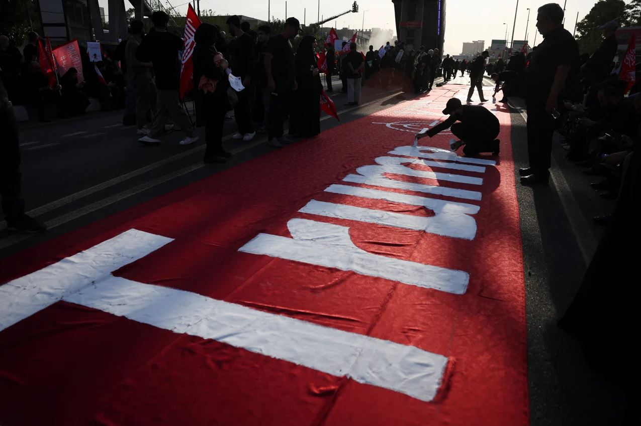 Άτομο γράφει το όνομα του προέδρου των ΗΠΑ, Ντόναλντ Τραμπ, σε πανό. Φωτογραφία: Majid Asgaripour / WANA News Agency / Reuters
