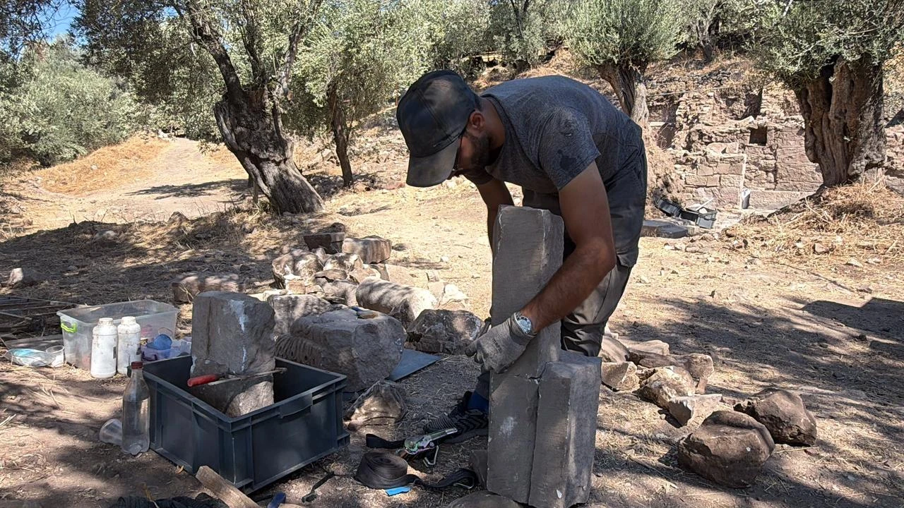Μέλος της ανασκαφικής ομάδας εργάζεται ανάμεσα σε αρχιτεκτονικά κατάλοιπα που αποκαλύφθηκαν στην αρχαία πόλη της Αντάνδρου στο Μπαλικεσίρ της δυτικής Τουρκίας. (Φωτογραφία: IHA)