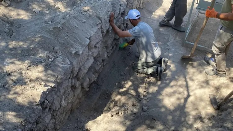 Ένας αρχαιολόγος εργάζεται κατά μήκος των σωζόμενων τοίχων των Ρωμαϊκών Δυτικών Λουτρών στο ιερό του Απόλλωνα Σμινθέα. Οι ανασκαφές αποκαλύπτουν σταδιακά τη διάταξη του κτιρίου. Πηγή: DHA