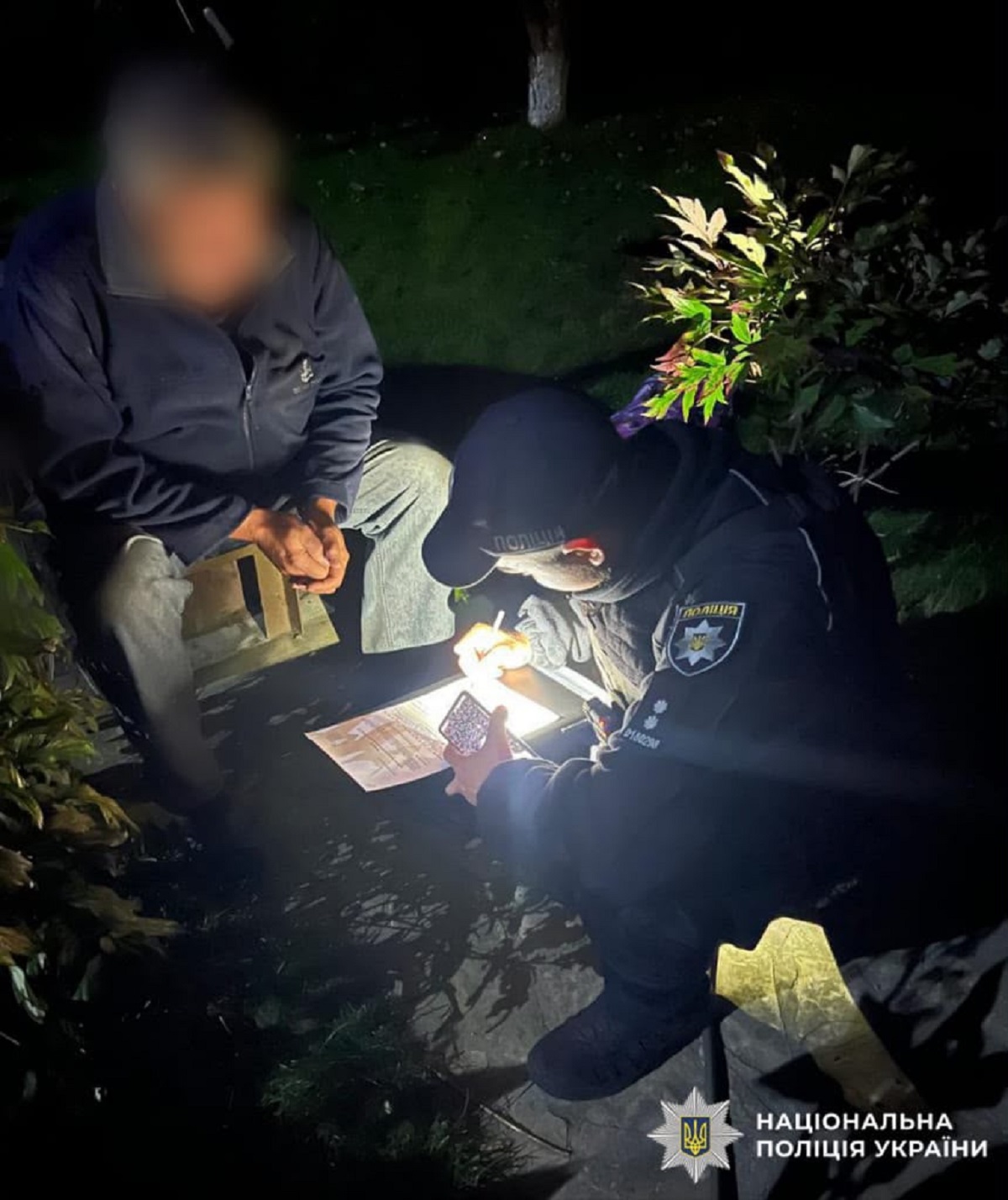 Αστυνομικός καταγράφει στοιχεία κατά τη διάρκεια της νύχτας, στο πλαίσιο της έρευνας για τις συνέπειες των ρωσικών πληγμάτων στην περιφέρεια του Κιέβου. Πηγή: Εθνική Αστυνομία της Ουκρανίας / Telegram.