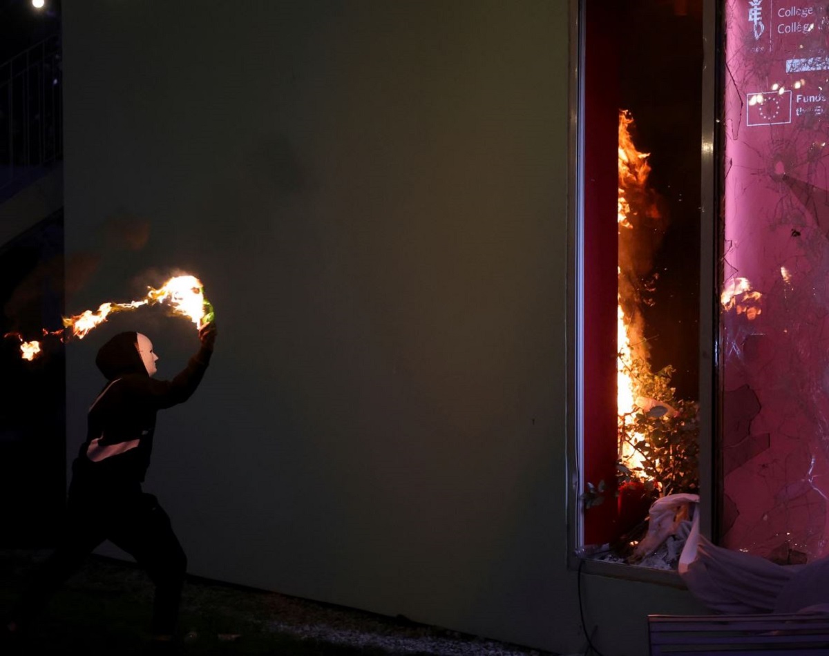 Κουκουλοφόρος διαδηλωτής εκτοξεύει βόμβα μολότοφ εναντίον του κτιρίου του Κολεγίου της Ευρώπης στα Τίρανα της Αλβανίας, το βράδυ της Τετάρτης (14/10), κατά τη διάρκεια των αντικυβερνητικών επεισοδίων. (Φωτογραφία: Hameraldi Agolli/AP)