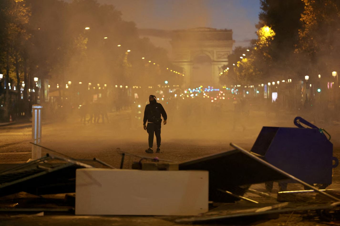 Διαδηλωτής περνά μέσα από σύννεφο δακρυγόνων κοντά σε οδόφραγμα στη λεωφόρο των Ηλυσίων Πεδίων, στο Παρίσι, κατά τη διάρκεια συγκρούσεων με την αστυνομία, στις 17 Οκτωβρίου 2026. Φωτογραφία: Stephanie Lecocq/Reuters