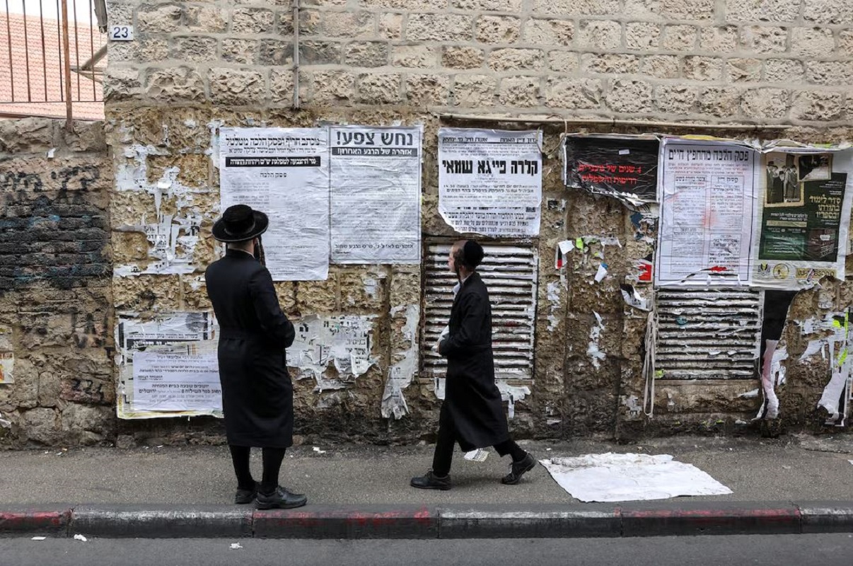 Υπερορθόδοξοι Εβραίοι διαβάζουν ανακοινώσεις αναρτημένες σε τοίχο στην Ιερουσαλήμ, κατά τη διάρκεια των βουλευτικών εκλογών στο Ισραήλ, την Τρίτη 27 Οκτωβρίου 2026. Φωτογραφία: Kevin Coombs / Reuters.