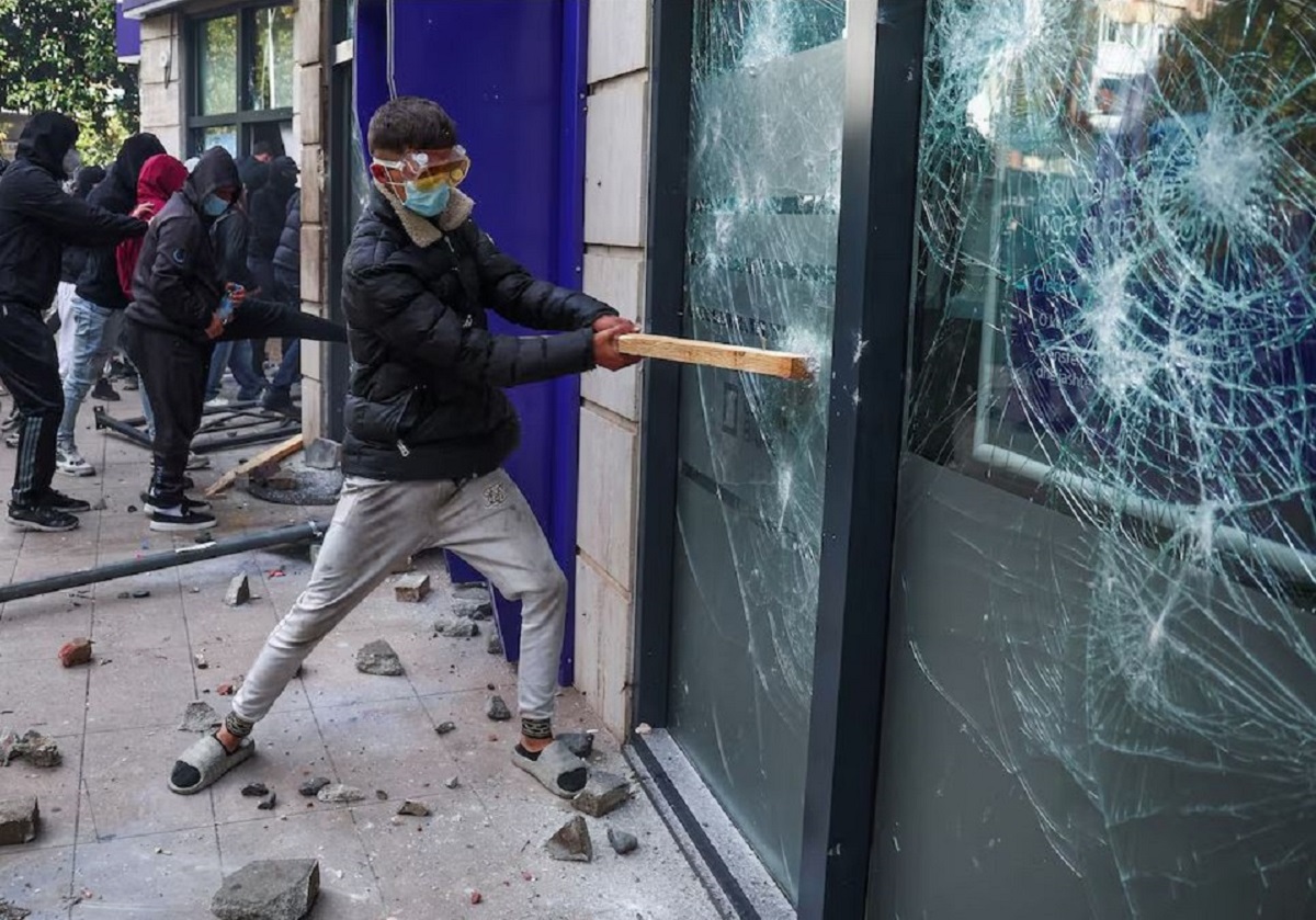 Διαδηλωτής σπάει τζάμι κατά τη διάρκεια συγκρούσεων με την αστυνομία στα Τίρανα, την Πέμπτη (15/10), καθώς κλιμακώνονται οι αντικυβερνητικές φοιτητικές κινητοποιήσεις στην Αλβανία. (Φωτογραφία: REUTERS/Florion Goga)