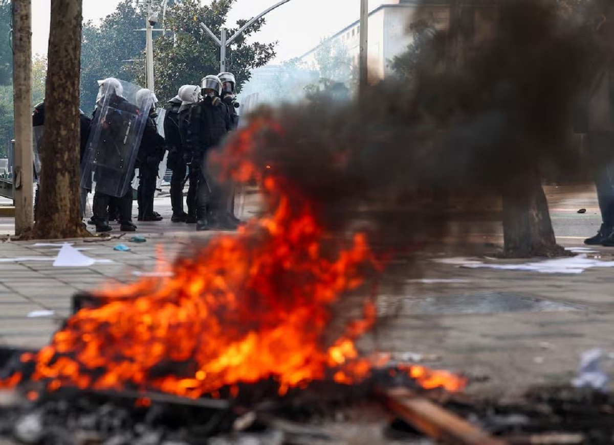 Φλόγες υψώνονται ενώ αστυνομικοί βρίσκονται στο σημείο των συγκρούσεων με διαδηλωτές, κατά τη διάρκεια αντικυβερνητικής φοιτητικής κινητοποίησης στα Τίρανα, την Πέμπτη (15/10). (Φωτογραφία: REUTERS/Florion Goga)